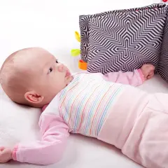 Niemowlę leży na plecach obok czarno-białej książeczki sensorycznej.